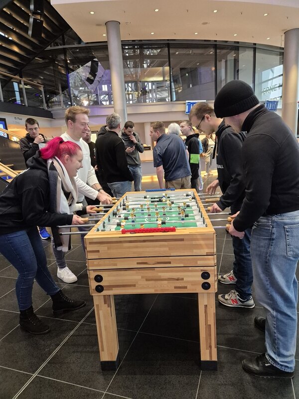 Teilnehmende spielen in der großen Halle der Gläsernen Manufaktur Tischfußball.