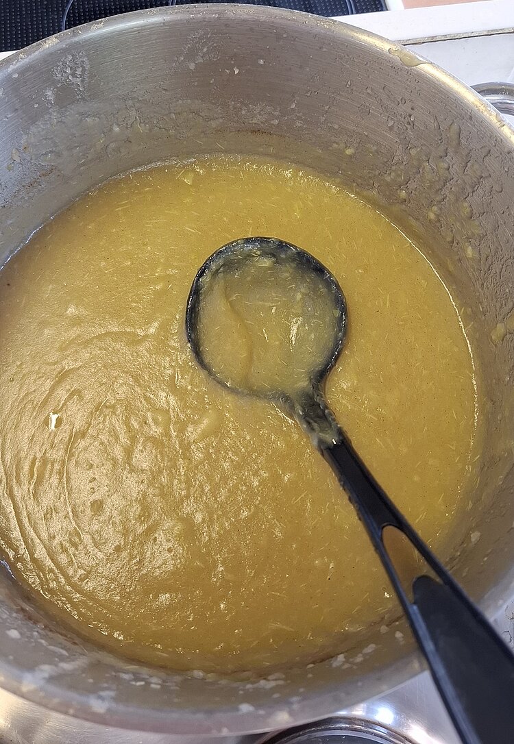 Fertig zubereitetes und fein püriertes Apfelmus in einer Schale, mit großer Schöpfkelle.