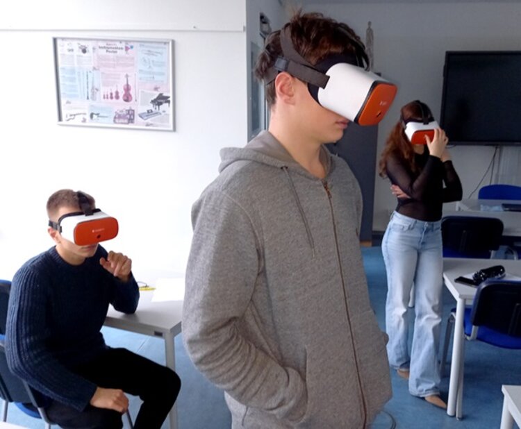 Drei Auszubildende haben Virtuell Reality-Brillen auf und erkunden Berufsbilder.
