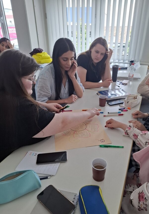 Teilnehmerinnen sitzen gemeinsam am Tisch und arbeiten konzentriert an ihren Präsentationen.