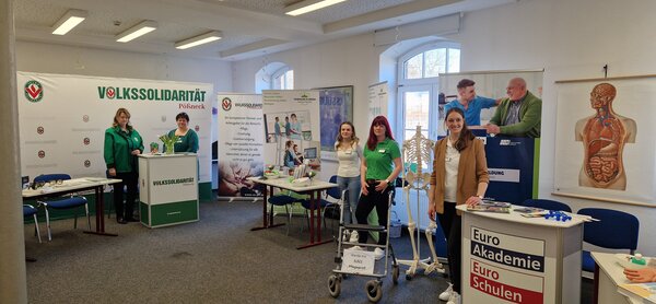 Mehrere Ausstellerinnen der Euro Akademie und Partner wie die Volkssolidarität stehen an Info-Ständen. Anatomische Modelle und Roll-ups verdeutlichen den Fokus auf Pflege- und Sozialberufe.