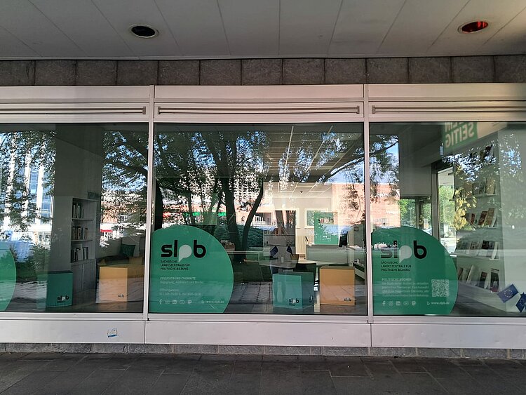 Ein Schaufenster der Landeszentrale für Politische Bildung mit dem grünen Wappen lpb und Werbematerialien.