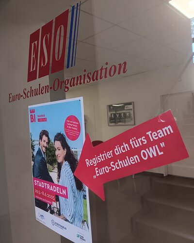 Ein Poster zur Aktion Stadtradeln in Bielefeld hängt an einer Glastür der Euro-Schulen Ostwestfalen-Lippe.