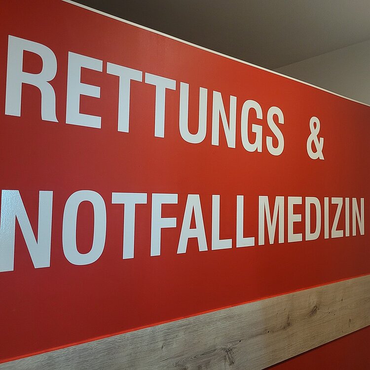 Die Nahaufnahme zeigt ein rotes Schild der "RETTUNGS & NOTFALLMEDIZIN".