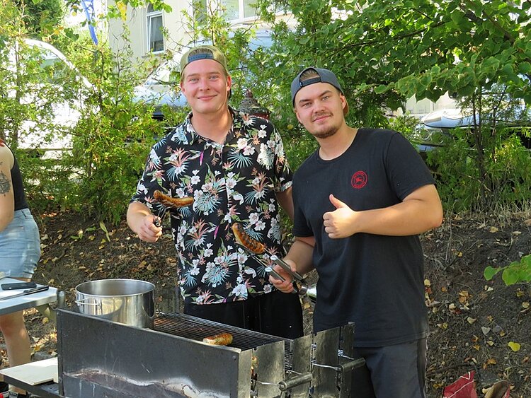 Der nächste Schritt unserer Klimaschule Zwei gute gelaunte, männliche Auszubildende grillen Würstchen für die Besucher*innen.