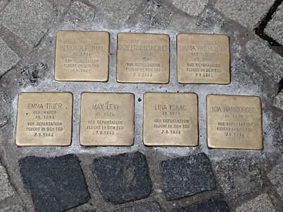 Sieben Stolpersteine im Kopfsteinpflaster mit eingravierten Namen und Daten zur Erinnerung an verfolgte jüdische Menschen; die Messingplatten sind in zwei Reihen angeordnet.