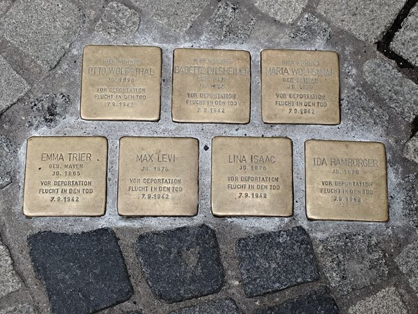 Sieben Stolpersteine im Kopfsteinpflaster mit eingravierten Namen und Daten zur Erinnerung an verfolgte jüdische Menschen; die Messingplatten sind in zwei Reihen angeordnet.