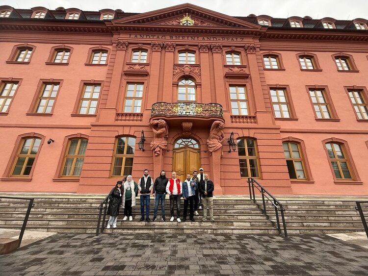 Die Teilnehmerinnen und Teilnehmer des Orientierungskurses an den Euro-Schulen Mainz posieren vor dem Landtag der Landeshauptstadt Mainz für ein Gruppenfoto.