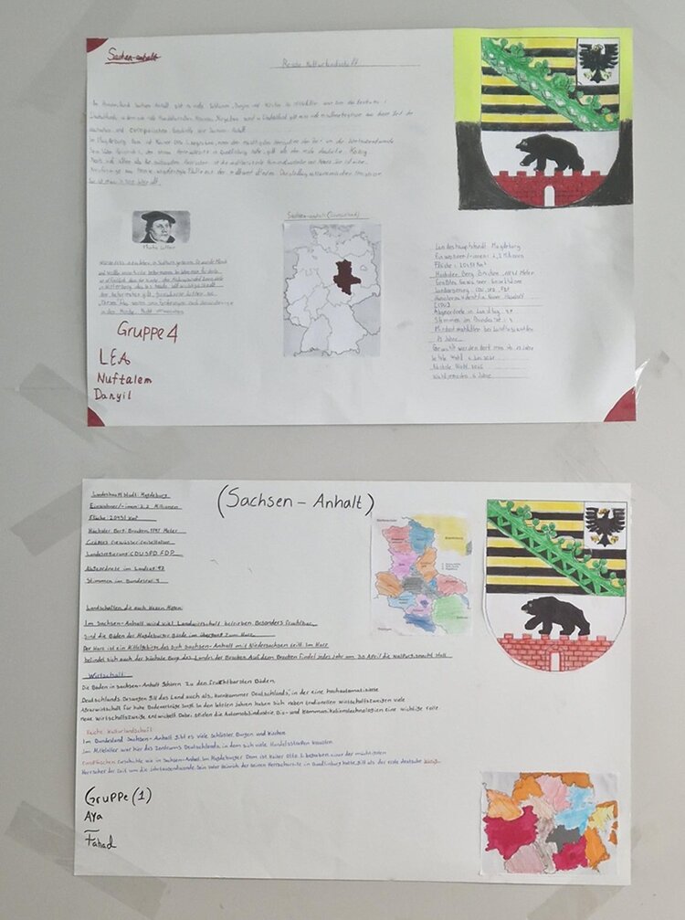 Zwei Din A4 große Zettel mit Informationen zu Sachsen-Anhalt kleben an der Wand, mit Landeswappen, Bundesländerkarte und Bild von Martin Luther.