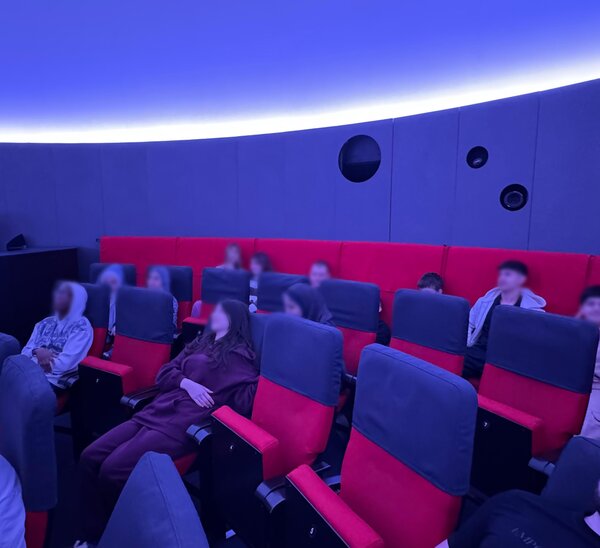 Foto von Schülern, die auf Kinosesseln im Planetarium Halle sitzen