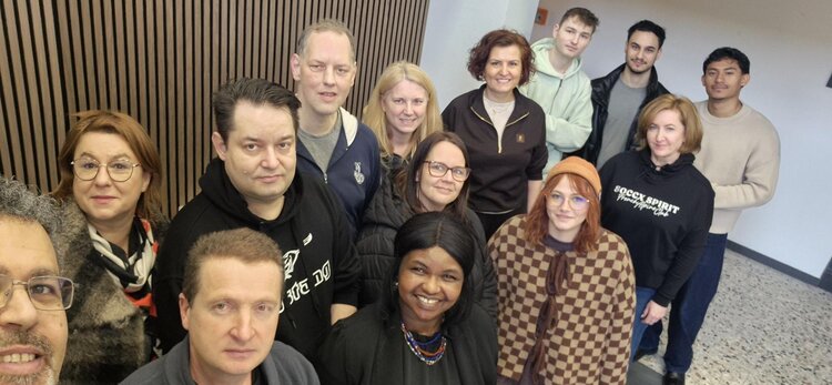 Gruppen-Selfie eines Teams aus mehreren Personen in einem Flur/Innenraum – alle schauen in die Kamera und wirken bereit für den Umzug.