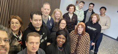 Gruppen-Selfie eines Teams aus mehreren Personen in einem Flur/Innenraum – alle schauen in die Kamera und wirken bereit für den Umzug.