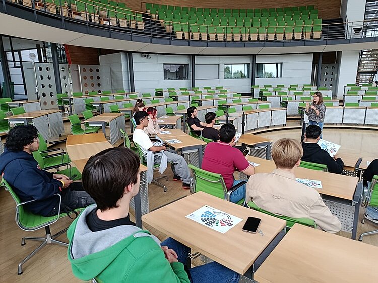 Jugendliche Teilnehmende des Integrationskurses an den Euro-Schulen Dresden sitzen im Plenarsaal des Sächsischen Landtags und hören einer Referentin zu, die vor zu ihnen spricht.