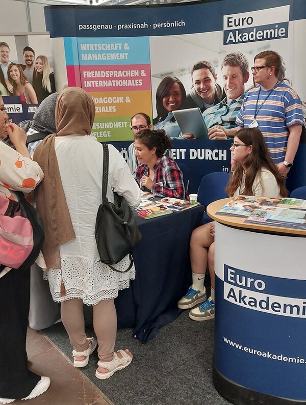 Messebesucherinnen und Messebesucher informieren sich und lassen sich am Euro Akademie Stand beraten.