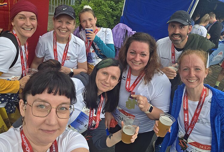 Euro-Schulen & Euro Akademie bei der Rewe Team Challenge 2025 Selfie von zehn Teammitgliedern mit Medaillen und Getränken. Alle strahlen und zeigen ihre Medaillen, die Stimmung ist ausgelassen und feierlich.