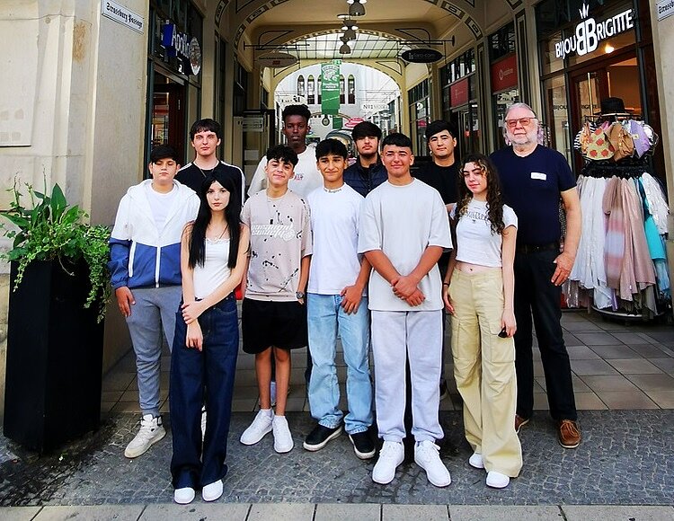 Schülerinnen und Schüler posieren draußen mit einer Lehrkraft für ein Gruppenfoto.