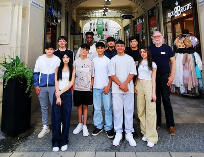 Schülerinnen und Schüler posieren draußen mit einer Lehrkraft für ein Gruppenfoto.