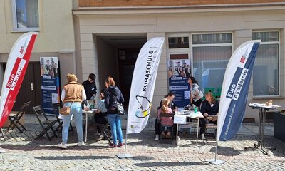 Menschen informieren sich am Stand der Euro Akademie und der Euro-Schulen Hohenstein-Ernstthal beim Frühlingsfest „HOT im Herzen“. Aufsteller und Banner zeigen das Bildungsangebot, während Kinder und Erwachsene an Tischen basteln.