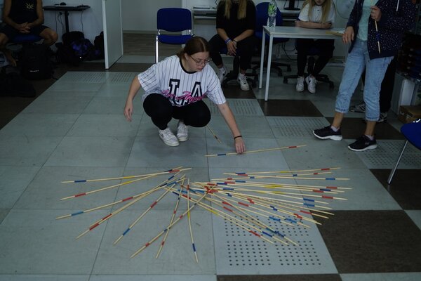 Geschicklichkeit und Ruhe. Beim Mikado versucht eine Teilnehmerin im schwarz-weiß gestreiften Shirt sich zu fokussieren und den richtigen Stab zu ziehen.