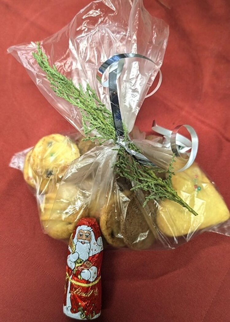 Durchsichtige Tüte mit selbstgebackenen Plätzchen, verziert mit kleinem Tannenzweig und Schokoweihnachtsmann.