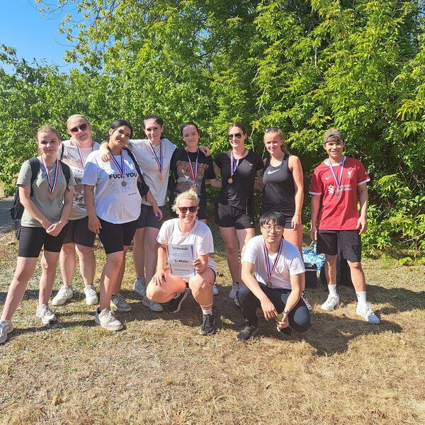 Die Drittplatzierten posieren mit ihrer Urkunde und Medaillen um den Hals für ein Gruppenfoto.