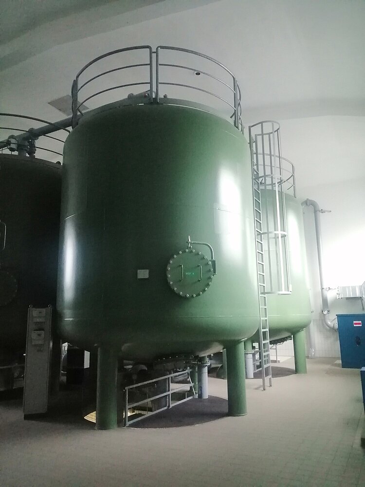 Exkursion des Berufssprachkurses B2 Aufnahme eines großen grünen Behälters, an dem eine Leiter nach oben führt, in einem Maschinenraum des Wasserwerks.