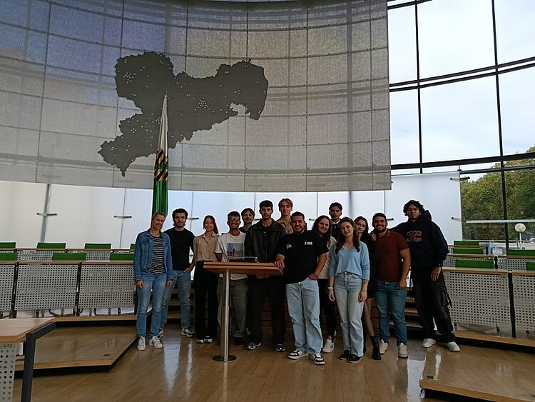 Die Teilnehmenden des Jugendintegrationskurses an den Euro-Schulen Dresden posieren im Plenarsaal des Sächsischen Landtags für ein Gruppenfoto.