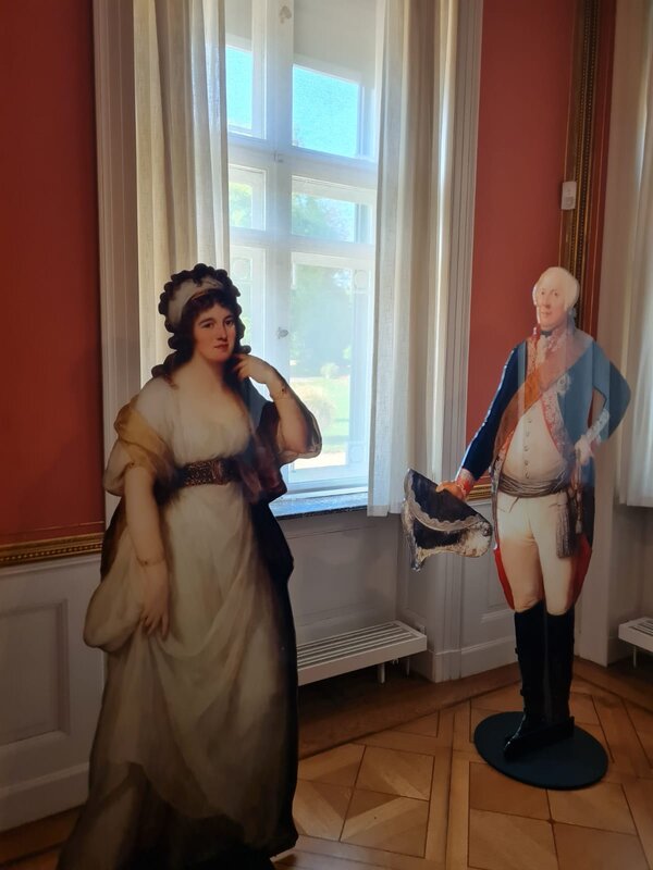 Zwei Figuren aus Pappe, die wahrscheinlich die ehemaligen adeligen Bewohner des Schlosses darstellen sind in einem Raum aufgestellt.