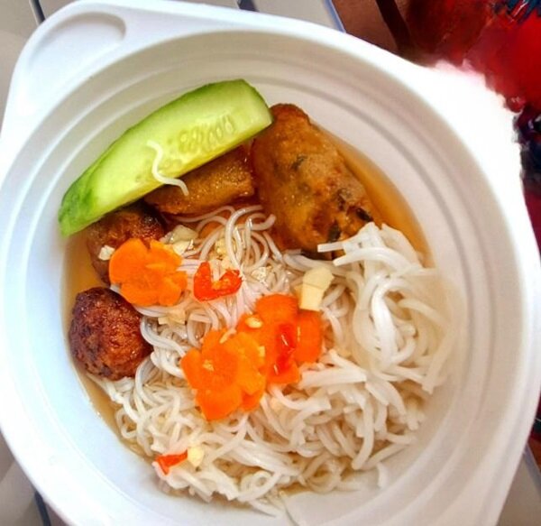 Teller mit vietnamesischem Gericht mit Glasnudeln, Gurke, Karotten, Teigröllchen und Fleischklößen.