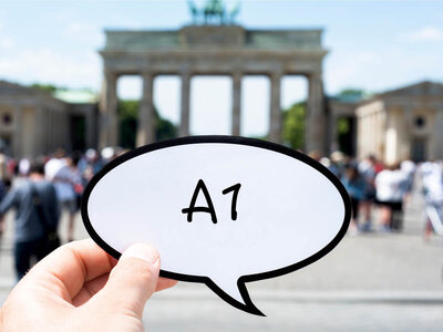Eine Hand hält eine Sprechblase mit der Aufschrift 'A1' in den Vordergrund. Im Hintergrund ist das Brandenburger Tor in Berlin zu sehen, umgeben von einer Menschenmenge. Das Brandenburger Tor ist ein historisches Wahrzeichen und ein beliebtes Touristenziel.