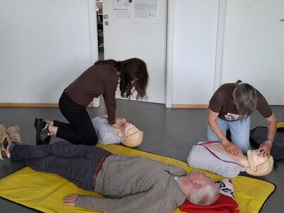 Mitarbeiter*innen der Euro-Schulen und Euro Akadmeie Trier knien auf dem Boden und üben an medizinischen Puppen eine Herzdruckmassage.