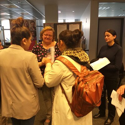Premiere gelungen: Fachbereich Soziales punktet auf Fachmesse der Arbeitsagentur Zwei Frauen, von denen man nur die Rückenansicht sieht, unterhalten sich mit einer Frau mit Brille. Rechts daneben steht eine vierte Frau, de nicht direkt am Gespräch beteiligt zu sein scheint, sondern eher etwas ungeduldig auf etwas wartet. Das Bild ist recht verschwommen.