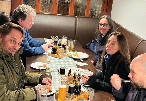 Drei männliche und zwei weibliche Mitarbeiter*innen der Euro-Schulen bzw. Euro Akademie, die zusammen an einem Tisch in einem Restaurant sitzen und etwas essen.