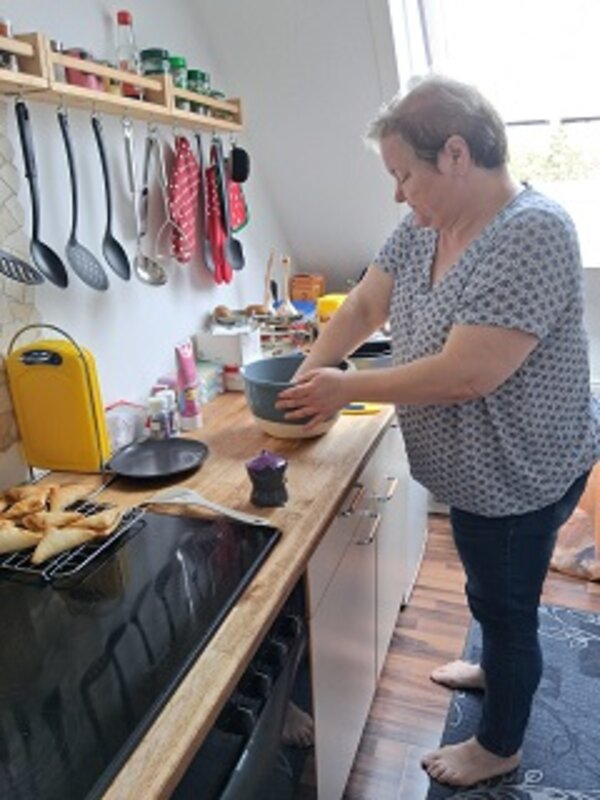 Mitarbeiterin steht in ihrer Küche und backt Kuchen und andere Teilchen.