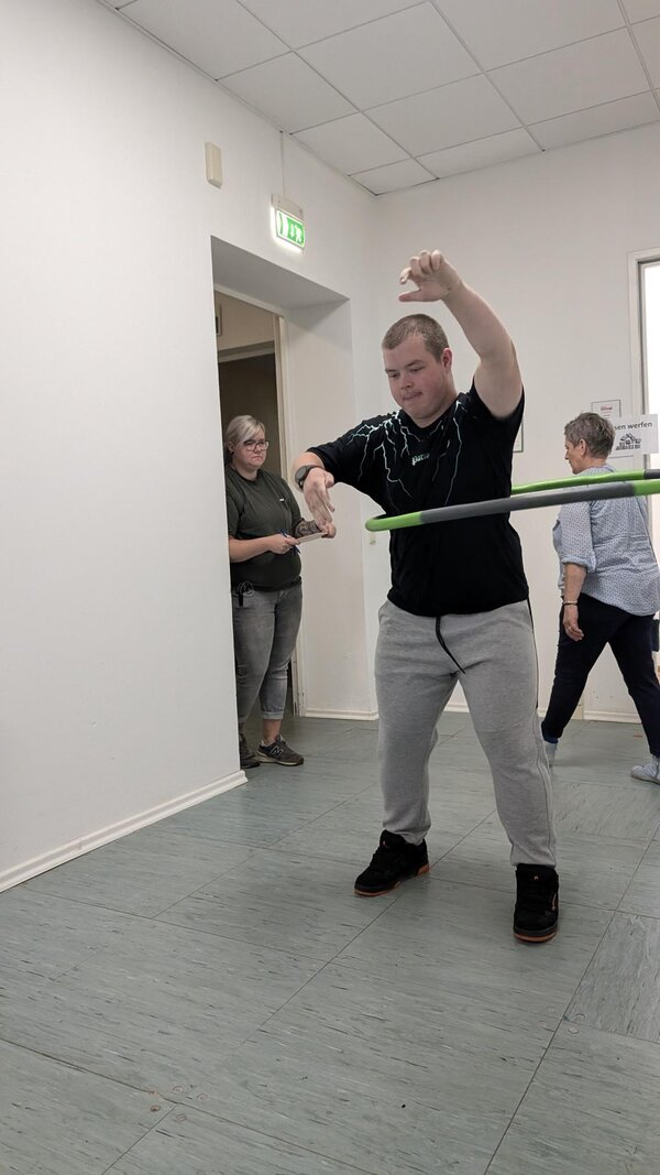 Geschicklichkeit und Ausdauer. Ein Teilnehmer muss mit einem Hula-Hoop-Reifen so viele Umdrehungen wie möglich schaffen.