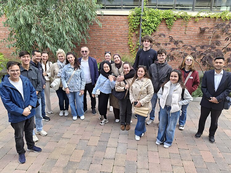 Die Kursteilnehmer*innen haben sich für ein Gruppenfoto vor der Halle versammelt.