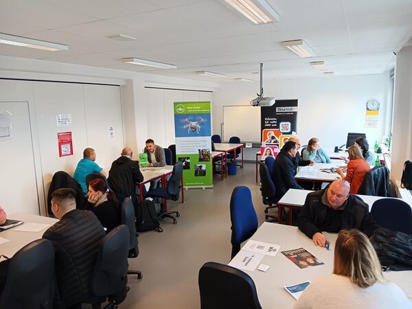 Teilnehmende sitzen potenziellen Arbeitgebern an Tischen gegenüber und lernen sich kennen.