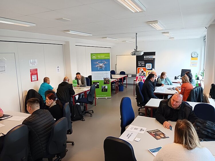 Job-Speed-Dating Teilnehmende sitzen potenziellen Arbeitgebern an Tischen gegenüber und lernen sich kennen.
