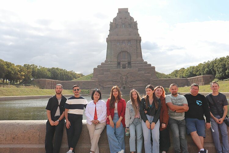 Unser Integrationskurs besucht Leipzig Elf Personen sitzen und stehen gemeinsam vor dem Völkerschlachtdenkmal in Leipzig.
