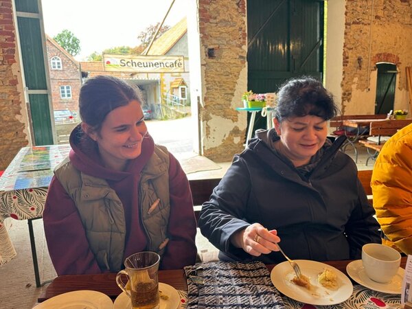 Zwei Teilnehmerinnen sitzen bei Kaffee, Tee und Kuchen im gemütlichen Scheunencafé.