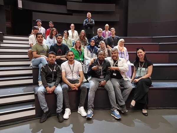 Für ein gemeinsames Gruppenbild posieren die Teilnehmenden gut gelaunt auf den Zuschauerplätzen des Fernsehstudios.