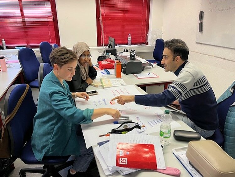 Erfolgreiche Gruppenarbeit im Berufssprachkurs Zwei Frauen und ein Mann arbeiten gemeinsam an einem Projekt.