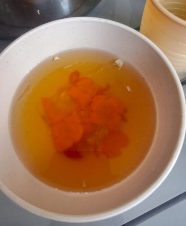 Teller mit Karottenscheiben in klarer Brühe.