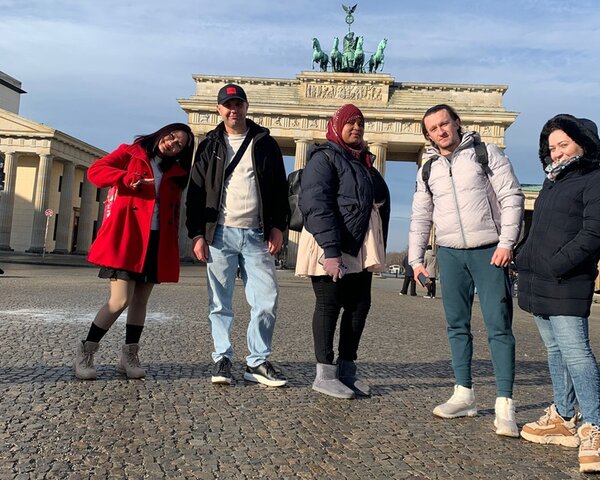 Teilnehmende posieren vor dem Brandenburger Tor für ein Gruppenfoto.