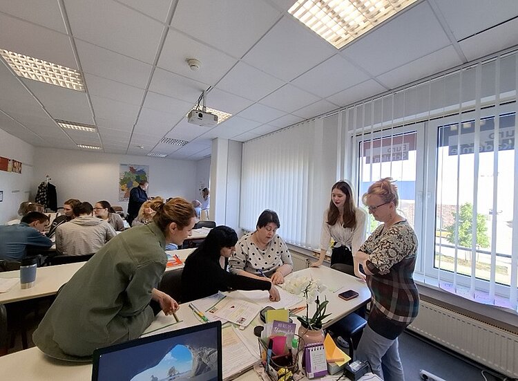 Blick in den Unterrichtsraum, in dem die Teilnehmenden in Gruppen zusammen arbeiten.
