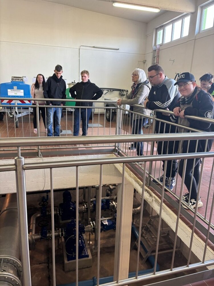Die Auszubildenden stehen in einer Halle der Wasserwerke Hoyerswerda und schauen am Treppengeländer stehend nach unten. 