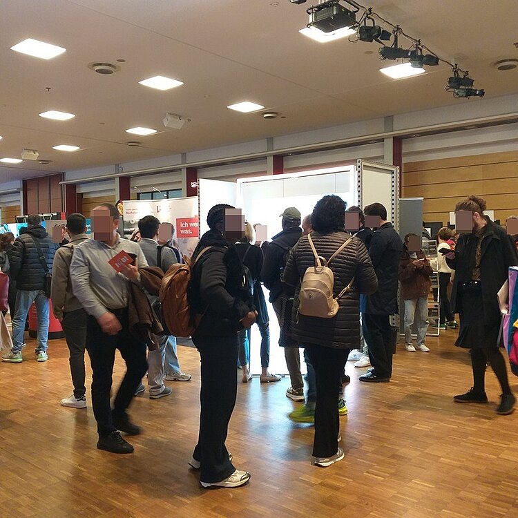 Auf der Jobmesse Karrieretag sind zahlreiche interessiert Messebesucherinnen und Besucher zu sehen.