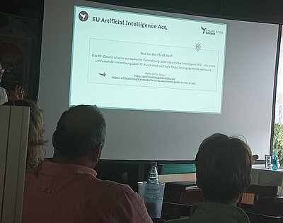 Sommerfest des DEHOGA-Landesverbandes Sachsen-Anhalt e. V. Teilnehmende sitzen in einem Raum und schauen auf eine an die Wand projizierte PowerPoint-Präsentation.