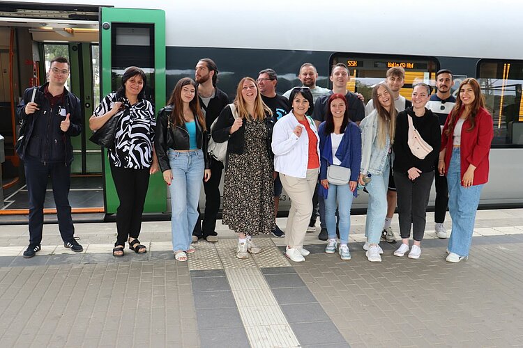 Unser Integrationskurs besucht Leipzig Gruppenfoto am Bahnsteig: Eine Gruppe von etwa 15 Personen steht vor einem Regionalzug.
