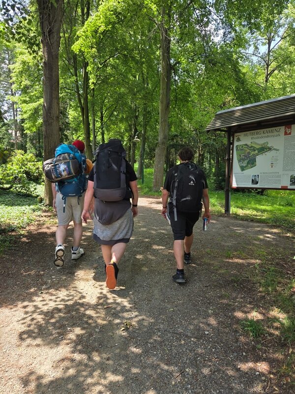 Die angehenden Fachlageristen pilgern durch den Wald und tragen alle große Rucksäcke. 